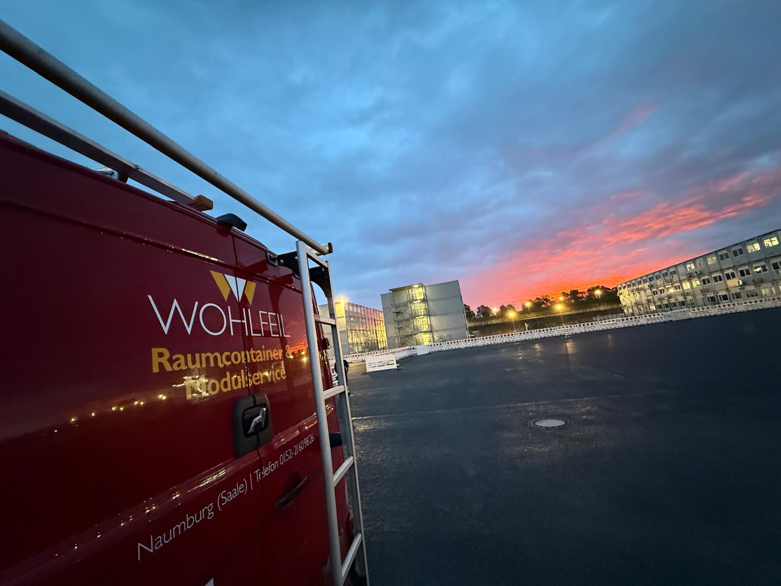 Containerbau in Dresden – Raumcontainer-Anlage im Morgenlicht mit WOHLFEIL-Servicefahrzeug