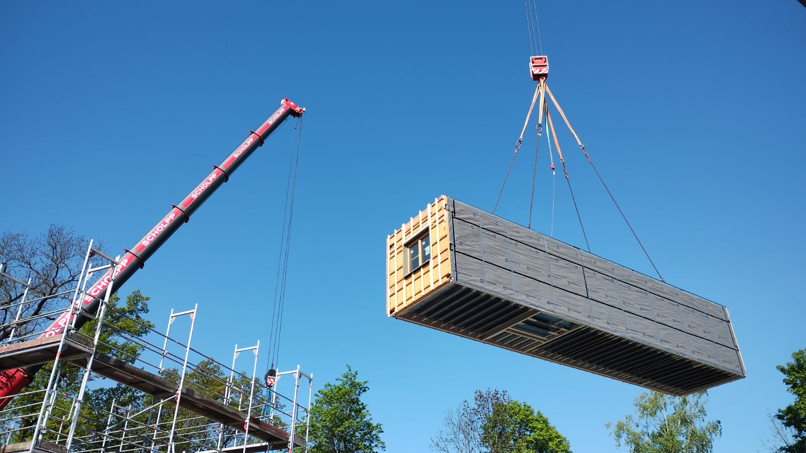 Modulbau in Bremen – Kran versetzt ein holzverkleidetes Raummodul – WOHLFEIL